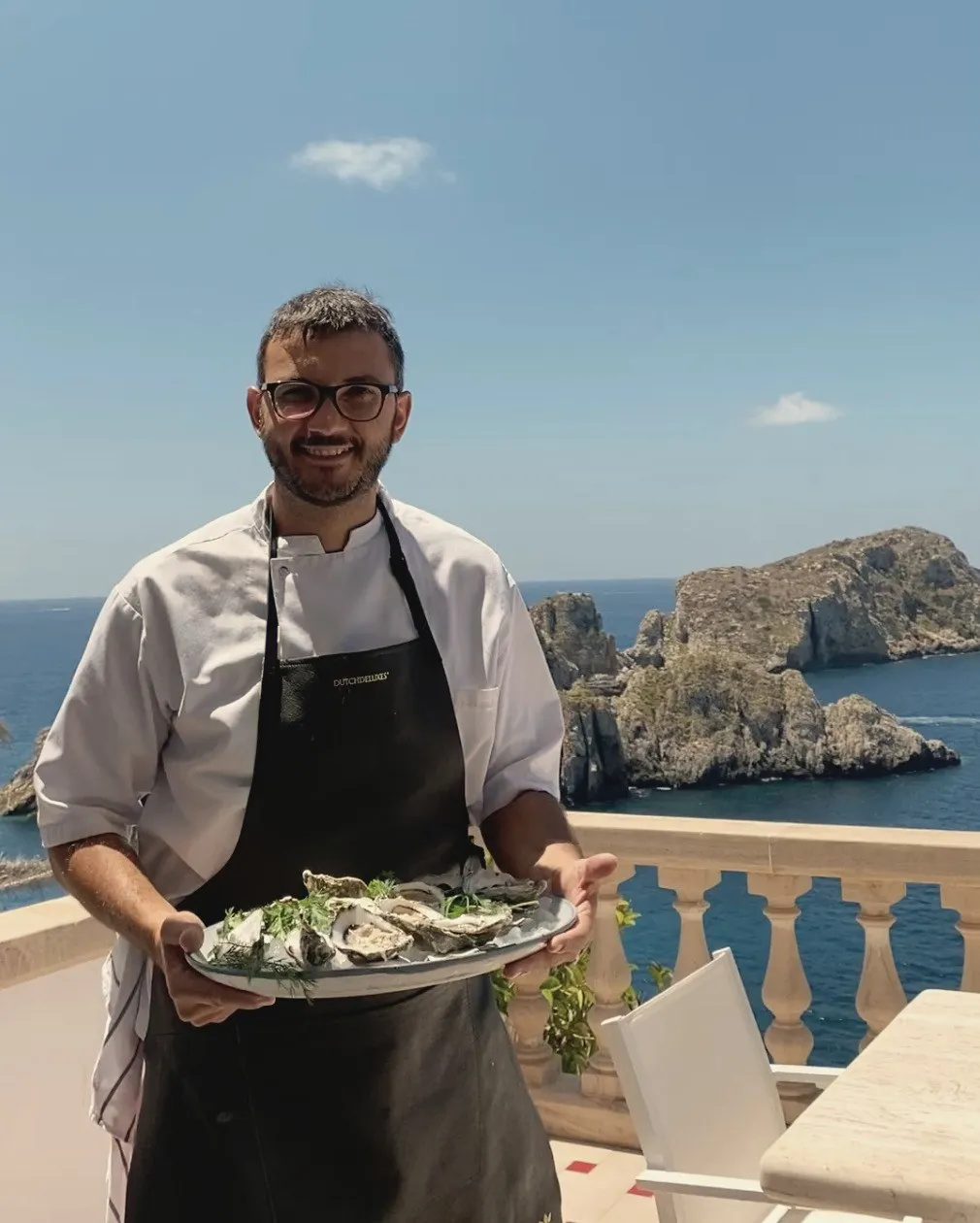 Chef Vincenzo Laudiero serving fresh oysters on a terrace above the sea